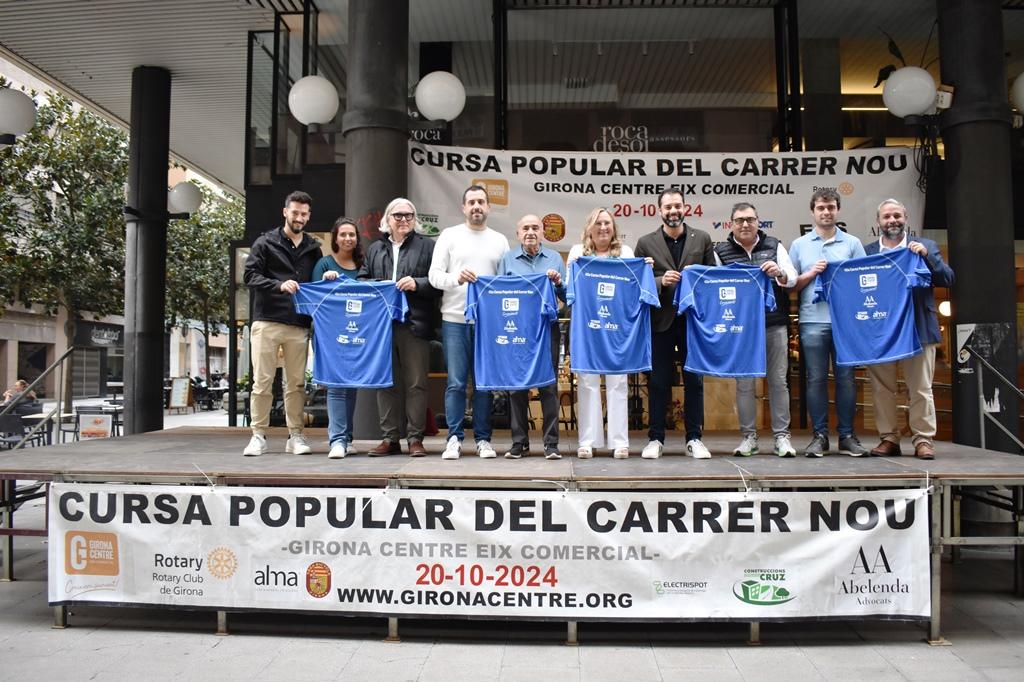 Els representants de Girona Centre Eix Comercial i l’Ajuntament de Girona (al centre) acompanyats dels principals patrocinadors d’aquest any, amb la samarreta de la 45a edició.